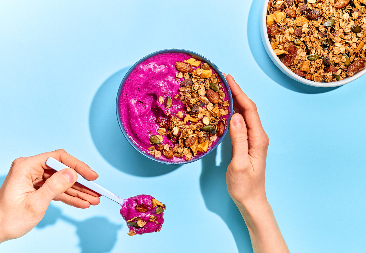 Granola aus der Pfanne auf Smoothie Bowl mit Hand